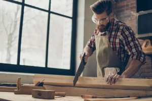 young-stylish-cabinet-maker-with--glasses-and-hairstyle--strong--handsome-craftsman-holding-saw-and-wood-blank-at-workplace-944613244-5af9afc2a18d9e003c17040c